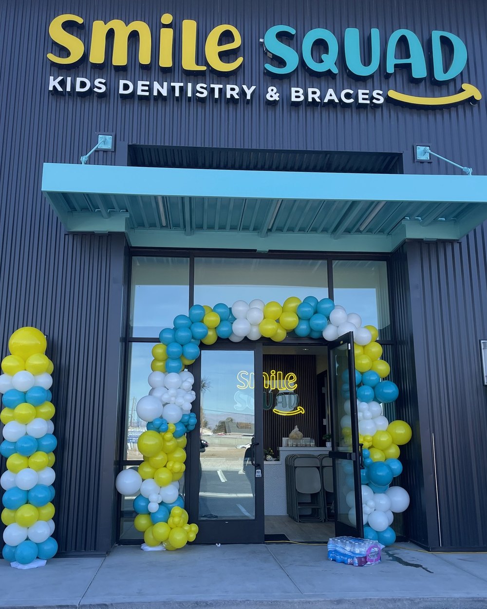 Balloon columns in blue, yellow and white on both sides of a kids dentistry entrance